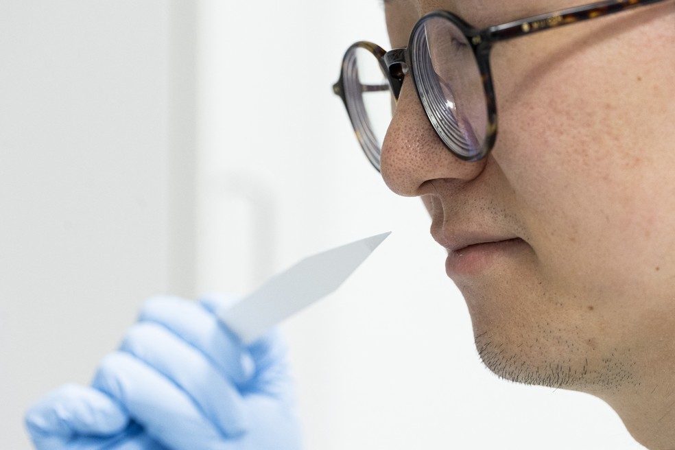 A perfumista júnior Shangyun Lyu cheira uma tira olfativa usada para avaliar fragrâncias na empresa Symrise — Foto: MICHAEL MATTHEY / AFP